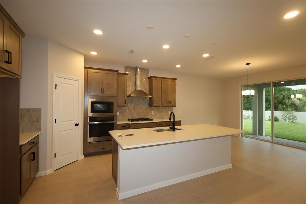 A kitchen with wood cabinets, a large island, stainless appliances, and tile flooring — 1314 HYDE STREET, ST CLOUD, FL