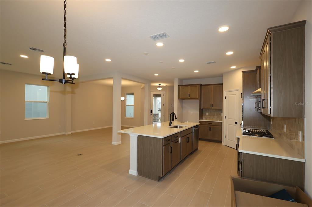 A modern kitchen with a large island and light wood-look tile flooring — 1314 HYDE STREET, ST CLOUD, FL