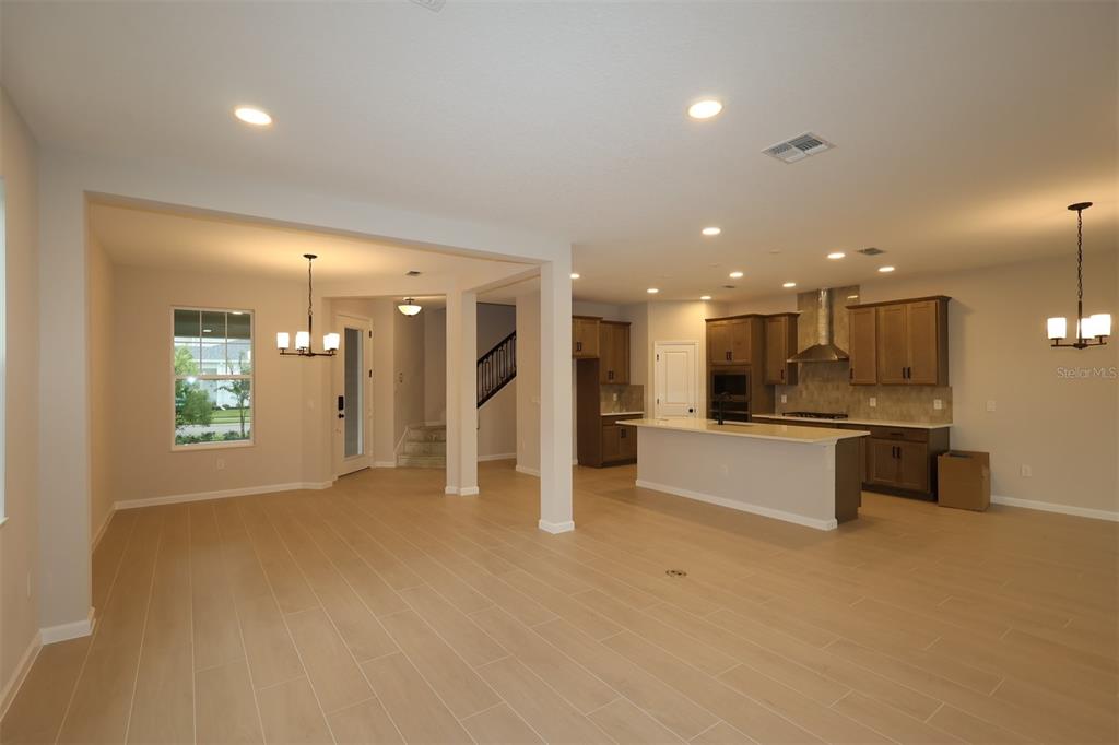 An open-concept kitchen and living area feature light wood-look tile flooring and recessed lighting — 1314 HYDE STREET, ST CLOUD, FL