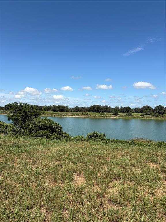 An aerial view shows a large pond surrounded by grassy fields, trees, and a distant road — 10349 COUNTY ROAD 555, FORT MEADE, FL