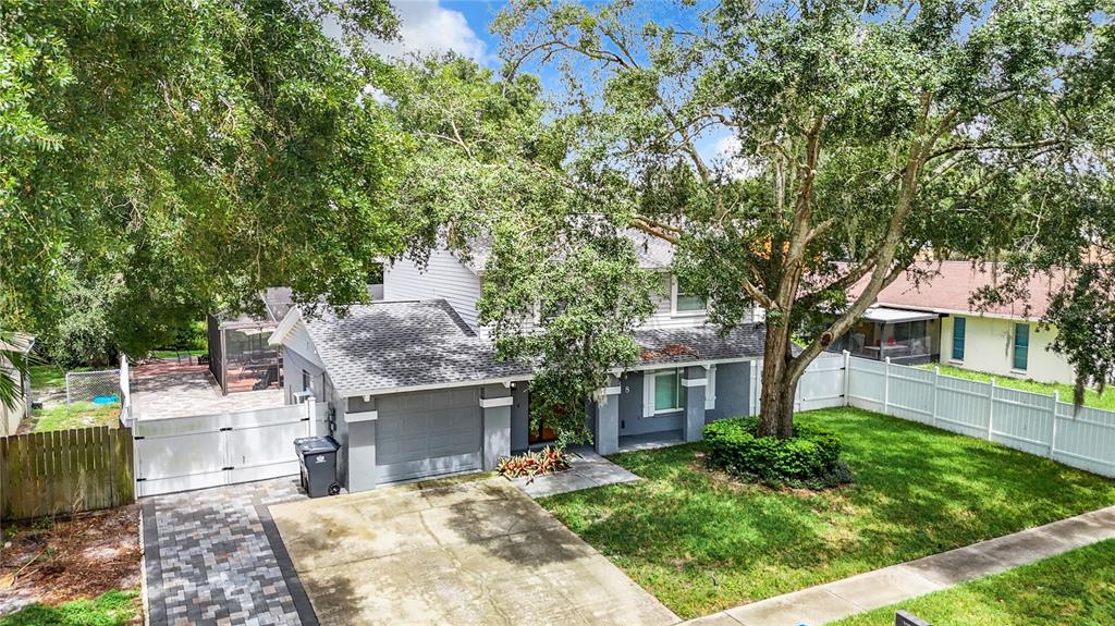 A two-story house with a gray exterior, a garage, and a large tree in front — 12438 CARDIFF DRIVE, TAMPA, FL