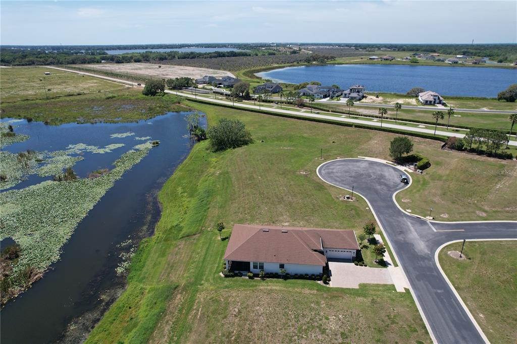 An aerial view shows a single-story house situated next to a pond and cul-de-sac — 116 N CALADIUM AVENUE, LAKE ALFRED, FL