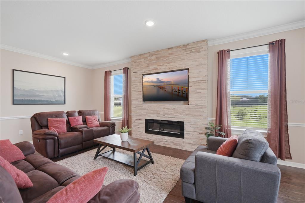 A living room features a stone fireplace with a mounted television and brown furniture — 9307 PARISIAN COURT, SEFFNER, FL