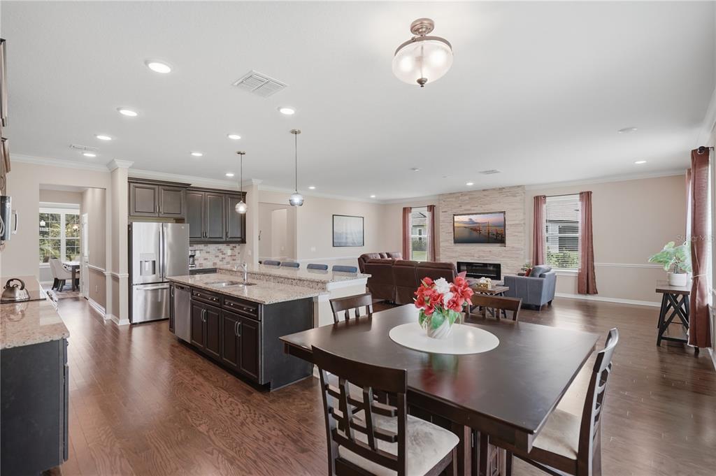 An open-concept kitchen and living area featuring dark wood cabinets, granite countertops, and hardwood floors — 9307 PARISIAN COURT, SEFFNER, FL