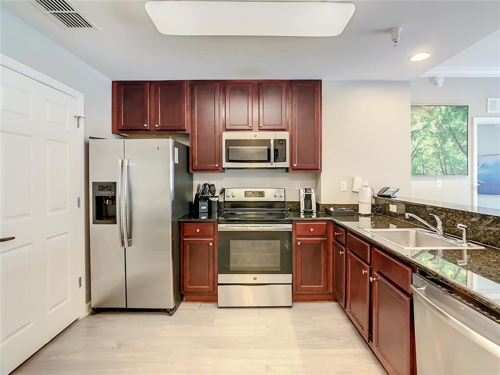 A kitchen features stainless steel appliances, dark wood cabinets, and granite countertops — 14501 GROVE RESORT AVE UNIT 1707, WINTER GARDEN, FL