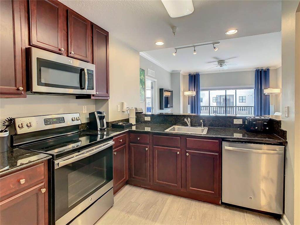 A kitchen with dark wood cabinets, stainless steel appliances, and a dark granite countertop — 14501 GROVE RESORT AVE UNIT 1707, WINTER GARDEN, FL