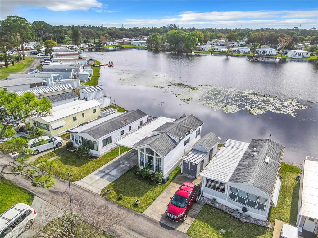 An aerial view shows several mobile homes situated along the edge of a lake — 92 EAGLE POINT S, OSTEEN, FL