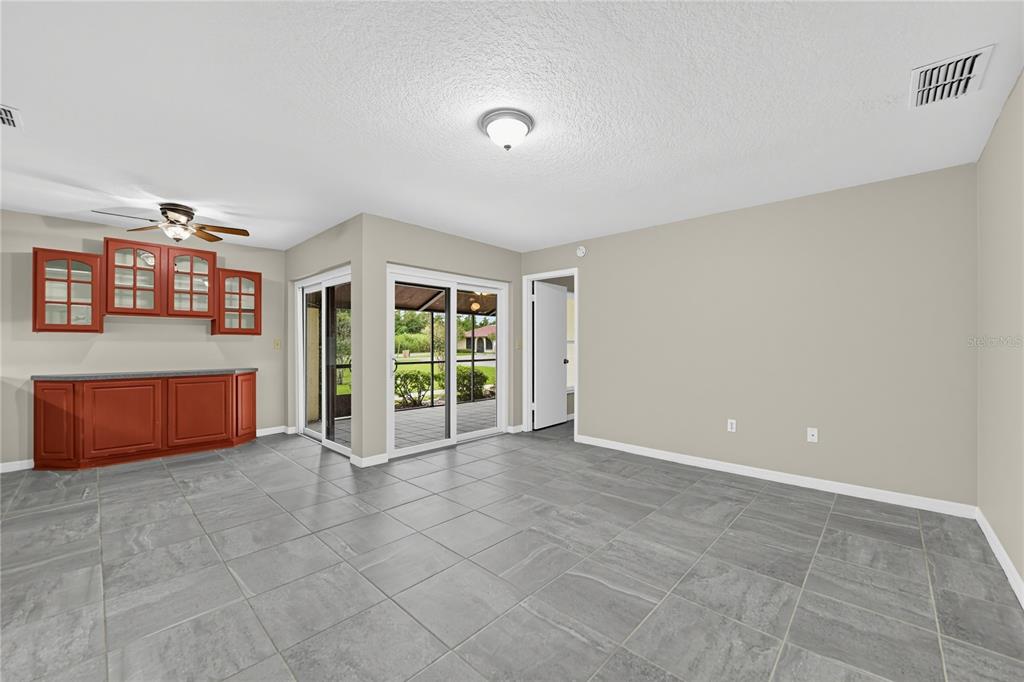 A room with gray tile flooring, a built-in wooden cabinet, and sliding glass patio doors — 523 HUNTER CIRCLE, KISSIMMEE, FL
