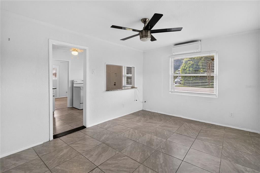 A bright room with white walls, tiled floors, a ceiling fan, and a pass-through window — 1103 BRACK STREET, KISSIMMEE, FL
