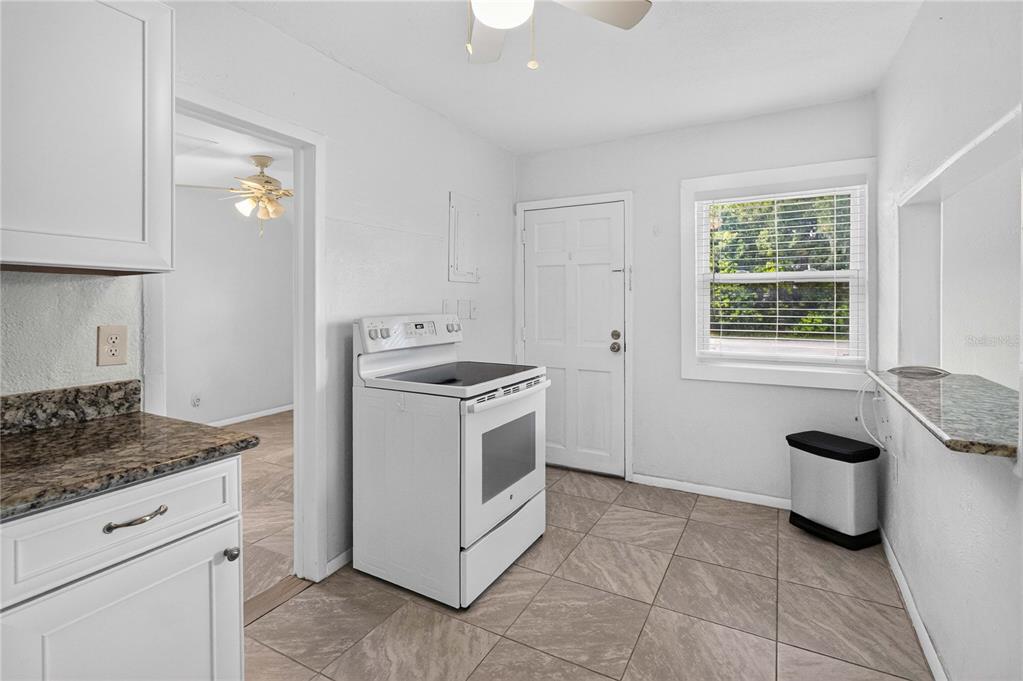A kitchen with white cabinets, granite countertops, a white stove, and tile flooring — 1103 BRACK STREET, KISSIMMEE, FL