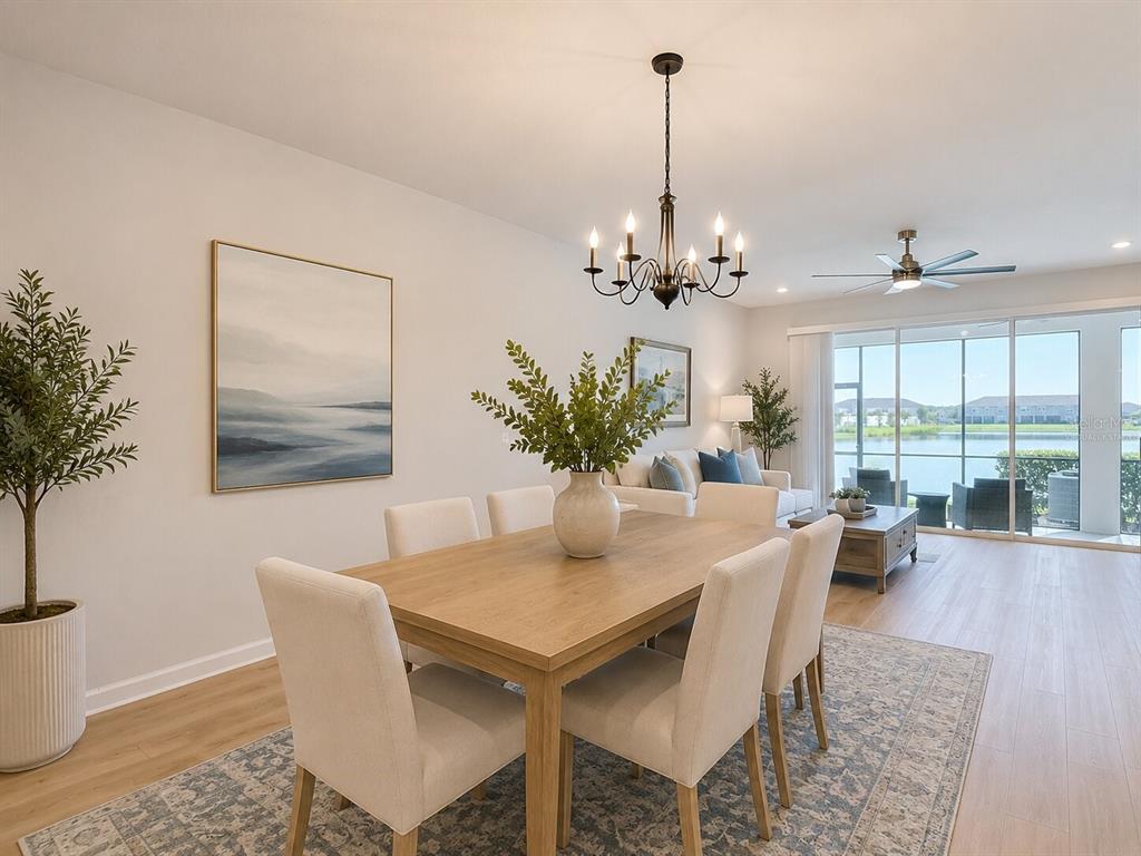 A dining area with a wooden table and chairs overlooks a lake through sliding doors — 2376 AUDUBON PRESERVE LANE, LUTZ, FL