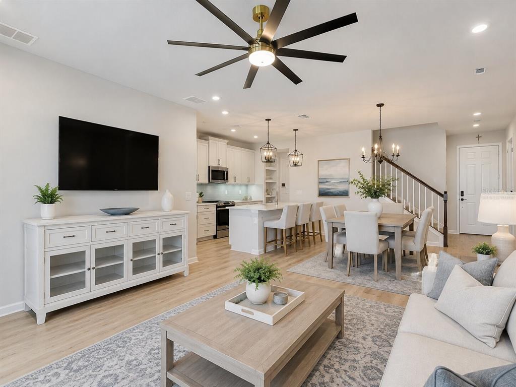 An open-concept living and dining area features a white kitchen, wood floors, and neutral furniture — 2376 AUDUBON PRESERVE LANE, LUTZ, FL