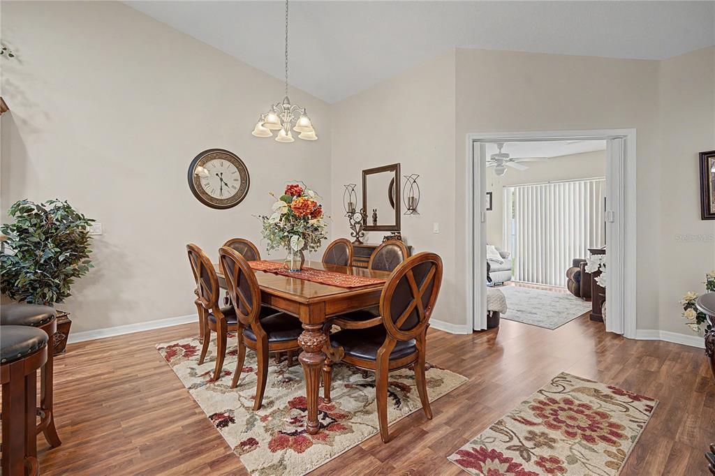 A dining room features a wooden table, six chairs, a chandelier, and wood-look flooring — 6783 BASSWOOD CIRCLE, ZEPHYRHILLS, FL