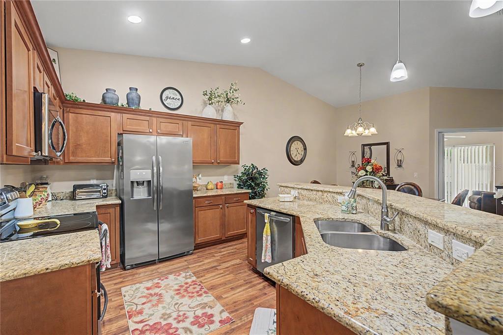 A kitchen features wood cabinets, granite countertops, stainless steel appliances, and a double sink — 6783 BASSWOOD CIRCLE, ZEPHYRHILLS, FL