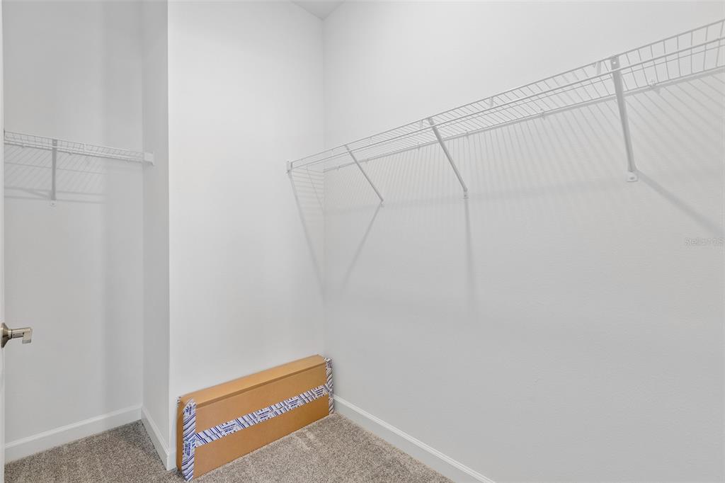 A walk-in closet features white walls, gray carpet, and white wire shelving — 3039 ADDISON BOULEVARD, ST CLOUD, FL
