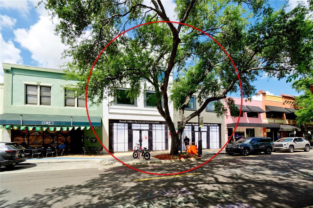 A white two-story commercial building with a large tree in front on a street — 420 12TH STREET W, BRADENTON, FL