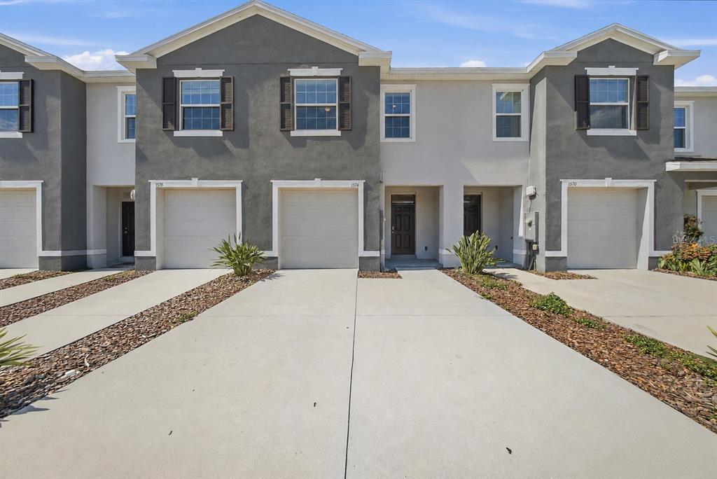 An open-concept living room and kitchen with tile flooring, gray cabinetry, and neutral furniture — 1574 HUBBELL ROAD, WESLEY CHAPEL, FL