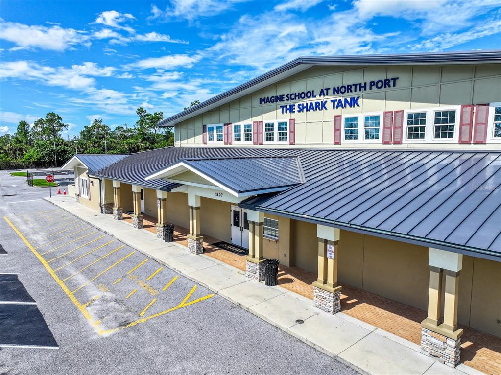 An exterior view of a school building with a metal roof and a parking lot — 2597 SYCAMORE STREET, NORTH PORT, FL