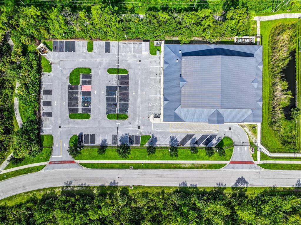 An aerial view shows a commercial building with a parking lot surrounded by green space — 2597 SYCAMORE STREET, NORTH PORT, FL