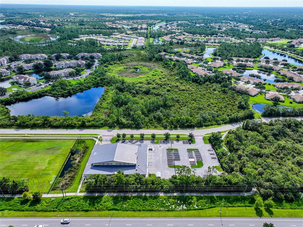 An aerial view shows a commercial building with a parking lot surrounded by green space — 2597 SYCAMORE STREET, NORTH PORT, FL