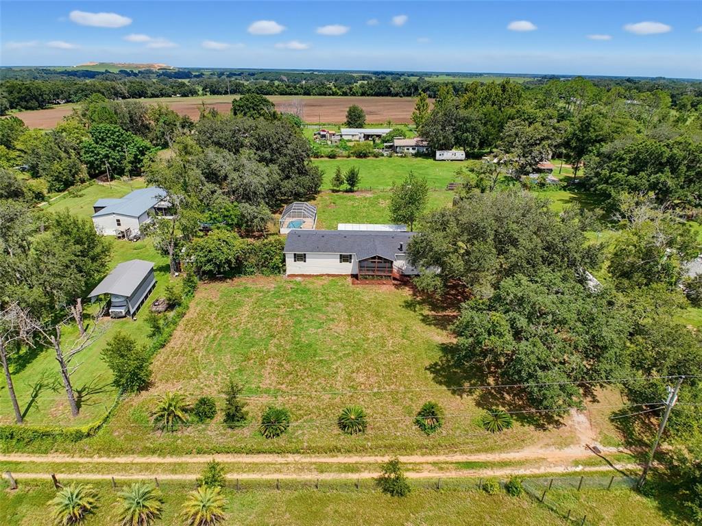 An aerial view shows a house with a pool and outbuildings on a rural lot — 11106 FERNWAY LANE, DADE CITY, FL
