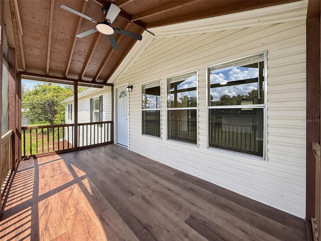 A covered porch features wood-look flooring, a ceiling fan, and white horizontal siding — 11106 FERNWAY LANE, DADE CITY, FL