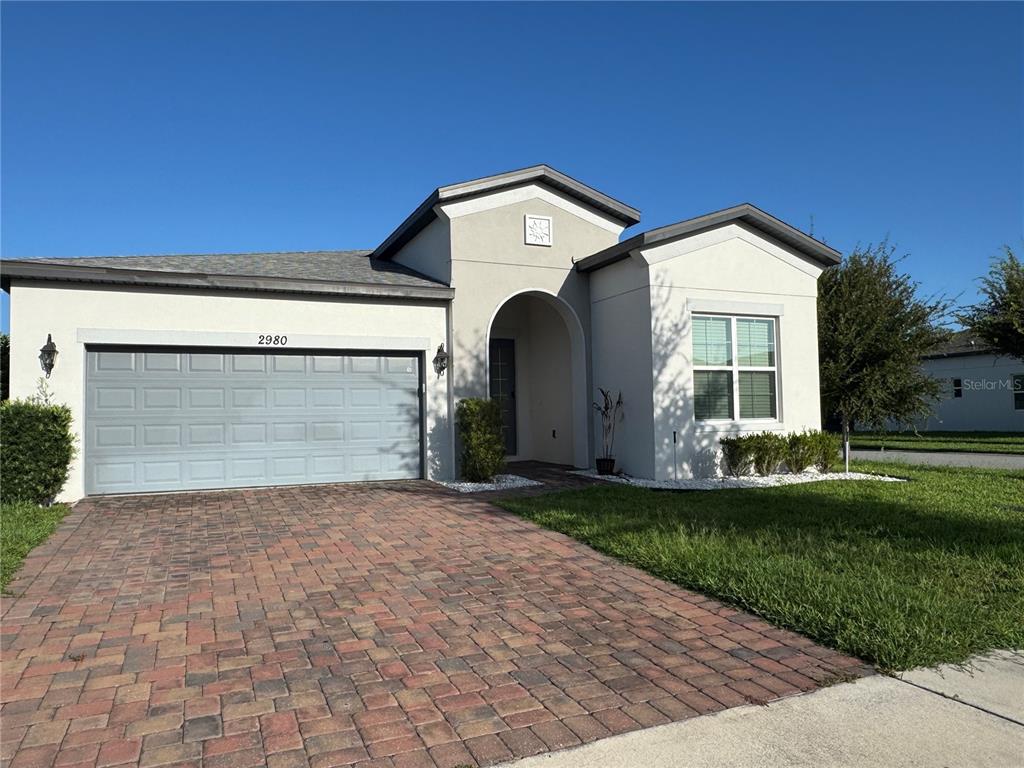 A single-story house with a gray garage door, a paved driveway, and a covered entryway — 2980 SCARLETT DRIVE, ST CLOUD, FL