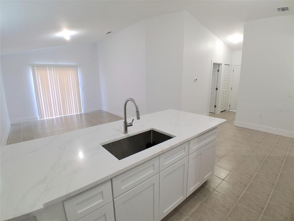A kitchen island with a white marble countertop and sink sits in a bright room — 1047 FLORIDA HOLLY DRIVE, ORLANDO, FL