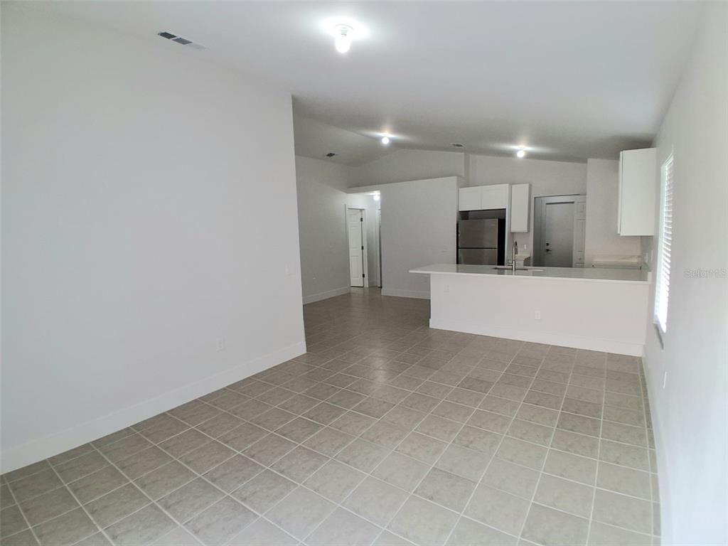 An open-concept kitchen and living area with white cabinets, tile flooring, and recessed lighting — 1047 FLORIDA HOLLY DRIVE, ORLANDO, FL