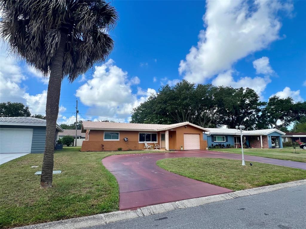 A single-story house with a red driveway, a palm tree, and a garage — 2133 INDIGO DRIVE, CLEARWATER, FL