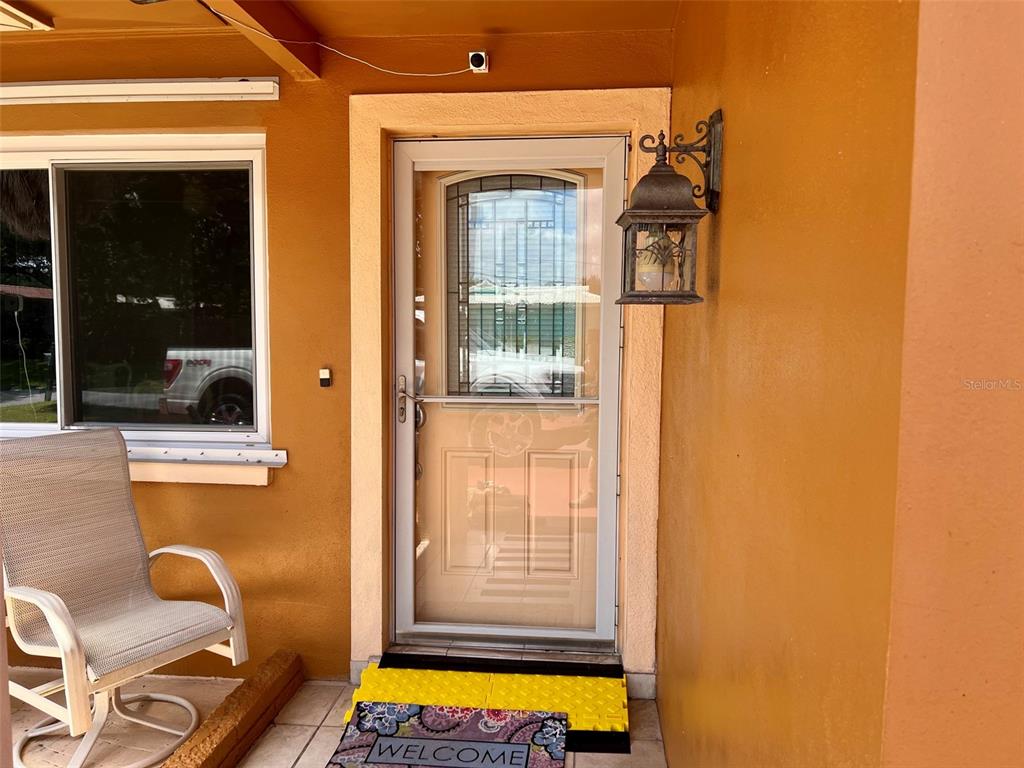 A front porch features a storm door, a wall-mounted lantern, and a rocking chair — 2133 INDIGO DRIVE, CLEARWATER, FL