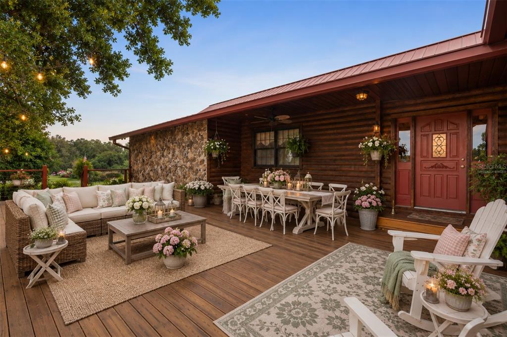 A spacious wooden deck features outdoor seating, a dining area, and a log cabin exterior — 35841 TIMBERTOP LANE, FRUITLAND PARK, FL