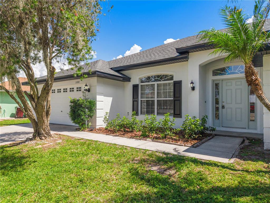 A single-story house with a white stucco exterior, a two-car garage, and a front walkway — 3207 SLATE ROAD, ST CLOUD, FL