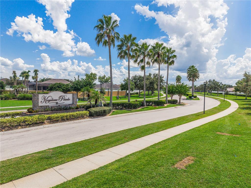 A stone monument sign for Keystone Pointe stands beside a road lined with palm trees — 3207 SLATE ROAD, ST CLOUD, FL