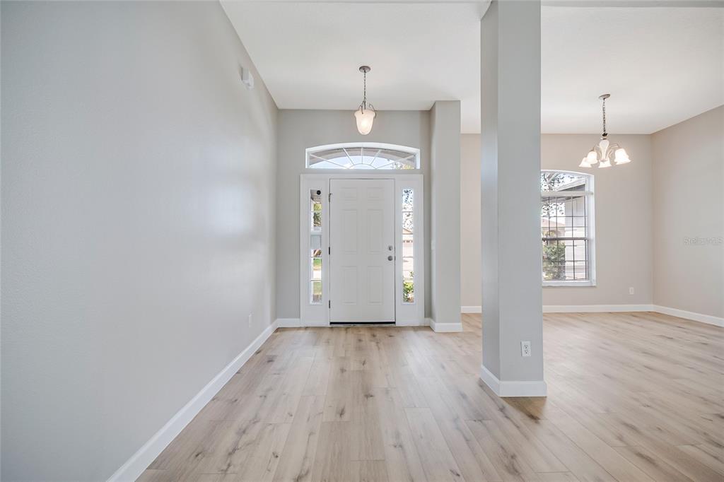 An entryway with light wood flooring, a white front door, and a central support pillar — 3207 SLATE ROAD, ST CLOUD, FL
