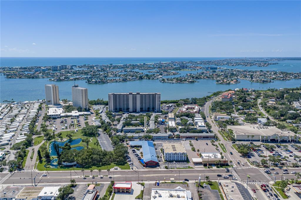An aerial view shows a multi-story apartment complex with a blue-roofed building in front — 1170 RUE DES CHATEAUX UNIT 1A, SOUTH PASADENA, FL