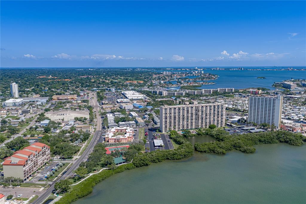 An aerial view shows high-rise apartment buildings, a coastal waterway, and surrounding suburban development — 1170 RUE DES CHATEAUX UNIT 1A, SOUTH PASADENA, FL