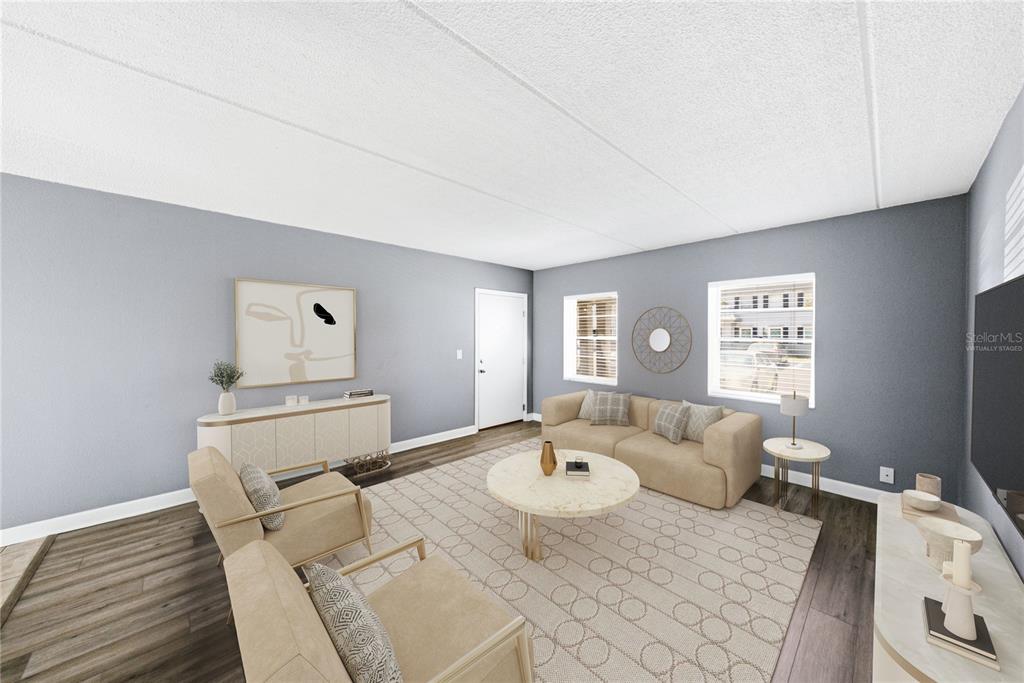 This is a virtually staged living room with gray walls, wood-look flooring, and neutral furniture — 1170 RUE DES CHATEAUX UNIT 1A, SOUTH PASADENA, FL