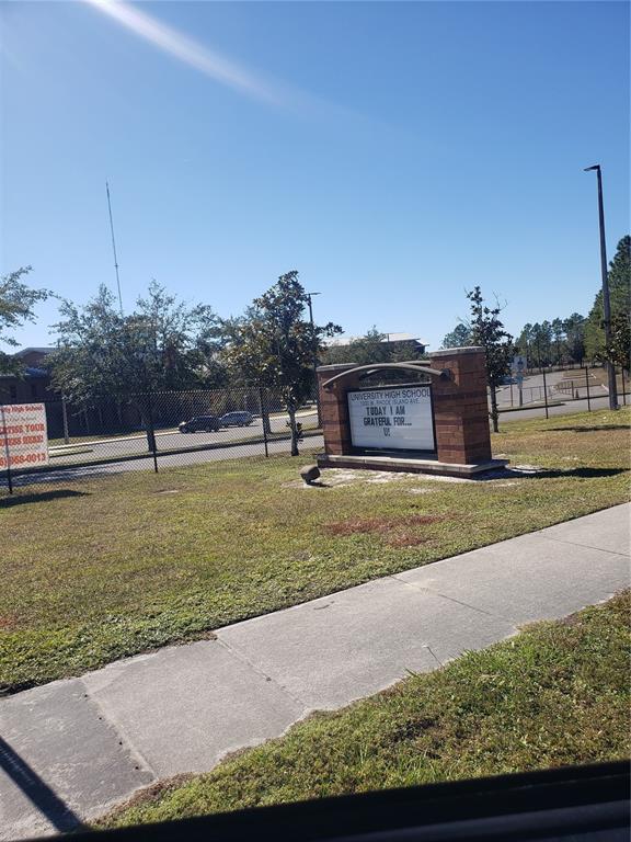 A brick monument sign for a high school stands on a grassy lawn near a sidewalk — CHESTNUT AVENUE, ORANGE CITY, FL