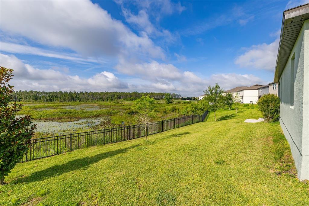 A covered patio features a gray sofa and a table overlooking a fenced grassy yard — 2236 DERWENT DRIVE, DAVENPORT, FL