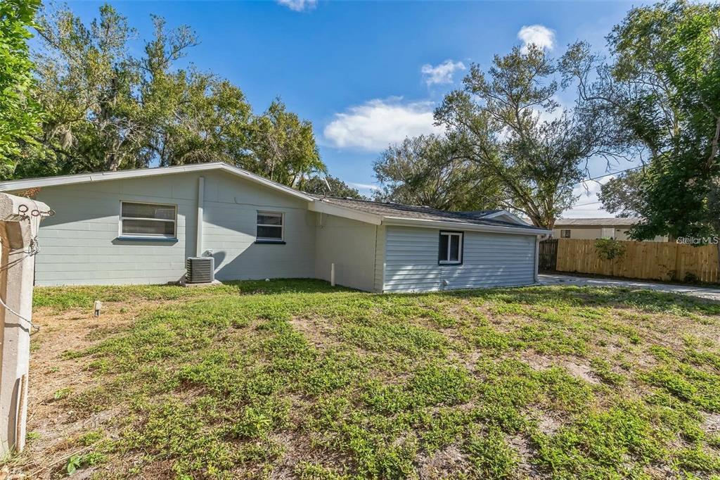 The exterior of a single-story house with light-colored siding and a grassy backyard — 403 PINEWOOD AVENUE, NOKOMIS, FL