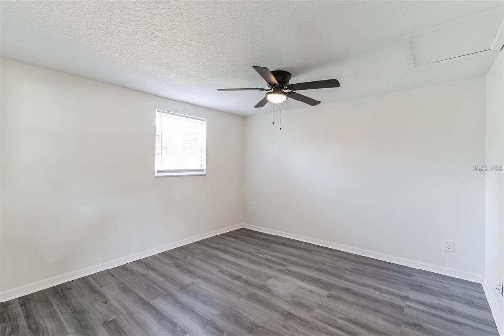 An empty bedroom features white walls, gray wood-look flooring, and a ceiling fan — 403 PINEWOOD AVENUE, NOKOMIS, FL