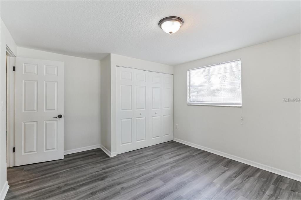 A bedroom with gray wood-look flooring, white walls, a white closet, and a ceiling light — 403 PINEWOOD AVENUE, NOKOMIS, FL