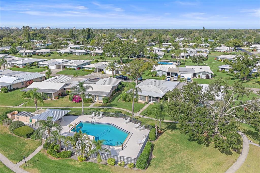 An aerial view of a community swimming pool surrounded by single-story homes and green lawns — 3286 BRUNSWICK LANE UNIT 704, SARASOTA, FL