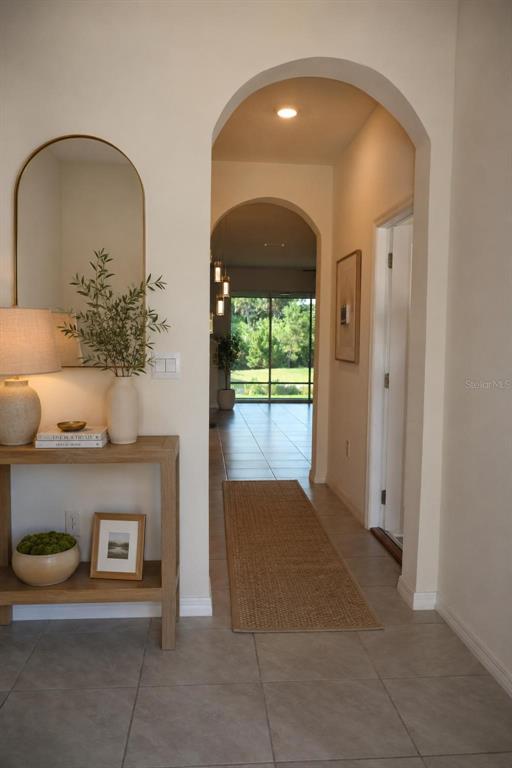 A tiled hallway features two arched doorways leading toward a view of the outdoors — 8748 MILESTONE DRIVE, SARASOTA, FL
