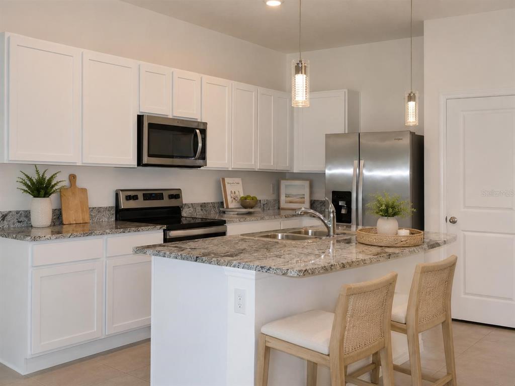 A kitchen with granite countertops and a pendant light overlooks a living area with tile — 8748 MILESTONE DRIVE, SARASOTA, FL