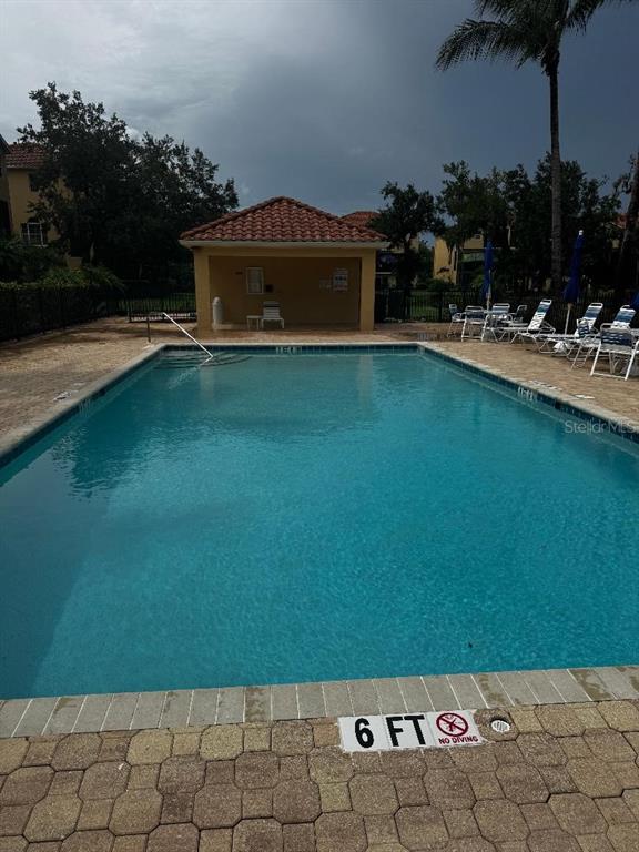An outdoor swimming pool with a depth marker and a covered pavilion in the background — 1205 3RD ST CIRCLE E, PALMETTO, FL