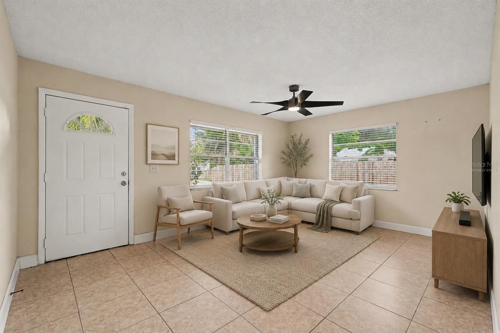 A living room features a sectional sofa, a coffee table, and tile flooring — 5733 66TH LANE N, ST PETERSBURG, FL