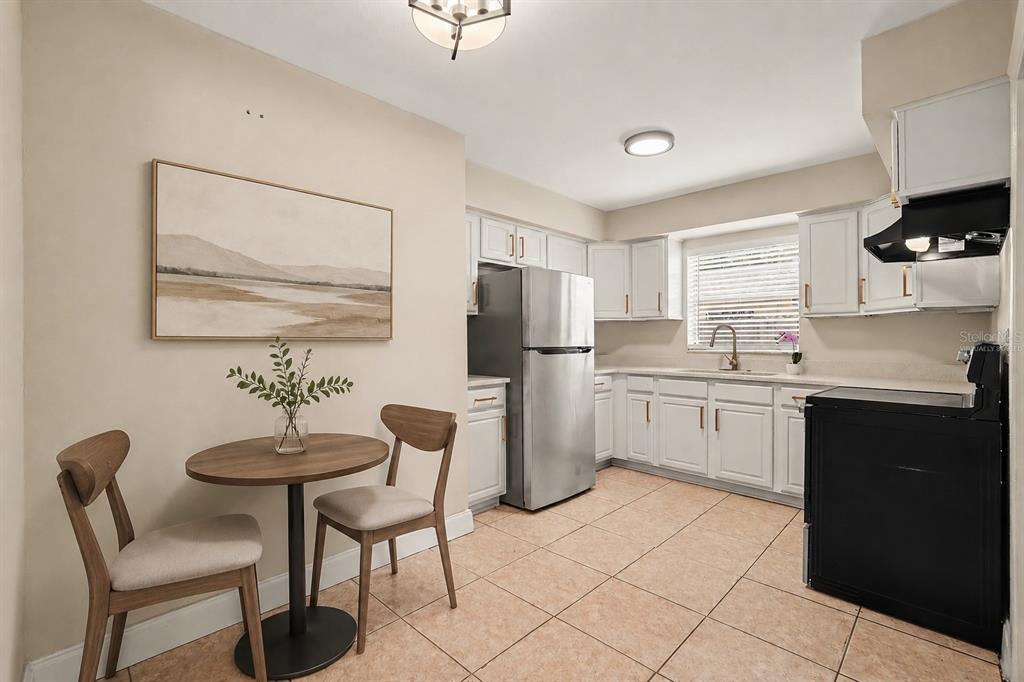 A kitchen features white cabinets, stainless steel appliances, tile flooring, and a small dining area — 5733 66TH LANE N, ST PETERSBURG, FL