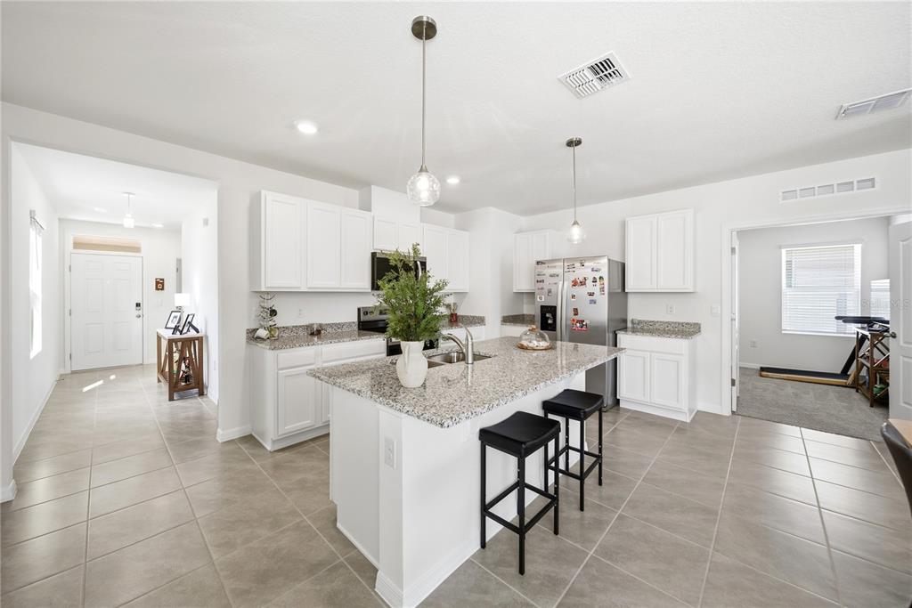 A single-story suburban house features a two-car garage, tan stucco siding, and a front porch — 7104 CATTLE EGRET DRIVE, ST CLOUD, FL